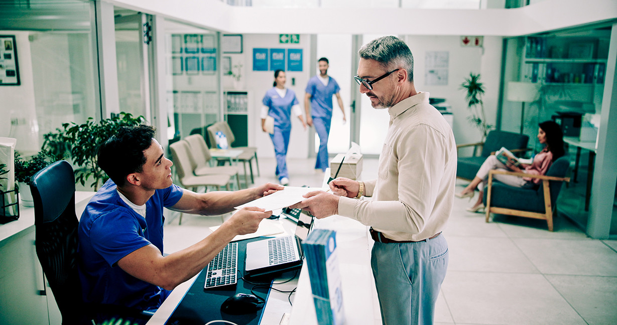 Hospital, nurse and man at front desk with paperwork for appointment, consultation and medical service. Healthcare, clinic and mature patient with admin for insurance, application form and documents