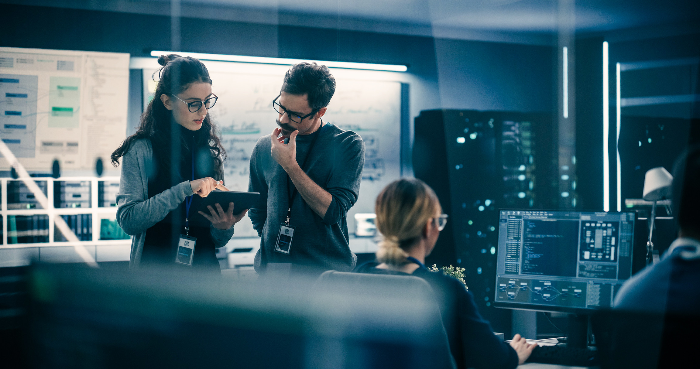 Portrait of Two Creative Young Female and Male Engineers Using Tablet Computer to Analyze and Discuss How to Proceed with the Artificial Intelligence Software. Standing in High Tech Research Office