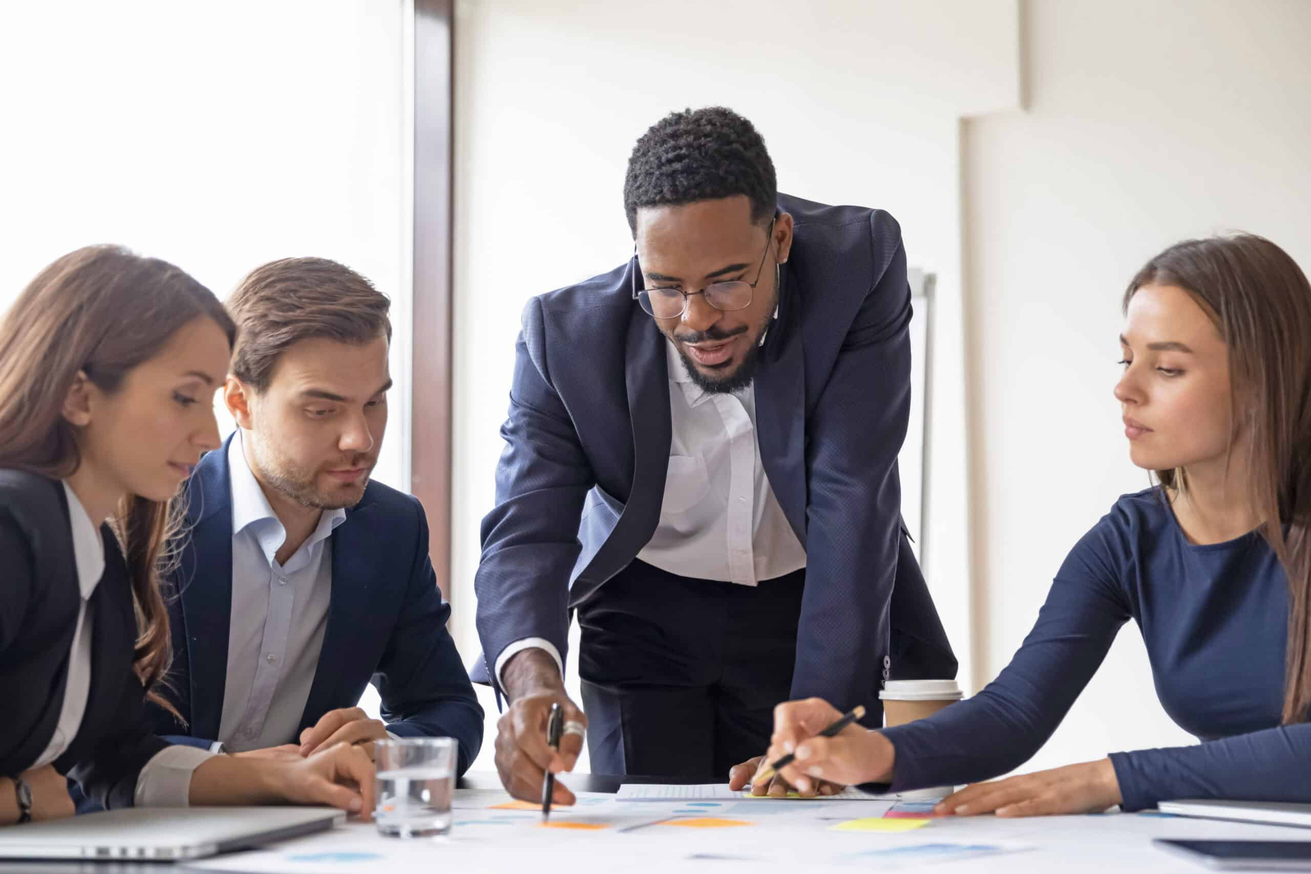 Business team collaborating around a table reviewing documents and data, representing teamwork, strategy, and decision-making.