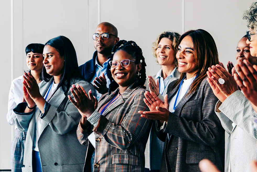 Diverse conference crowd clapping and smiling in a meeting room