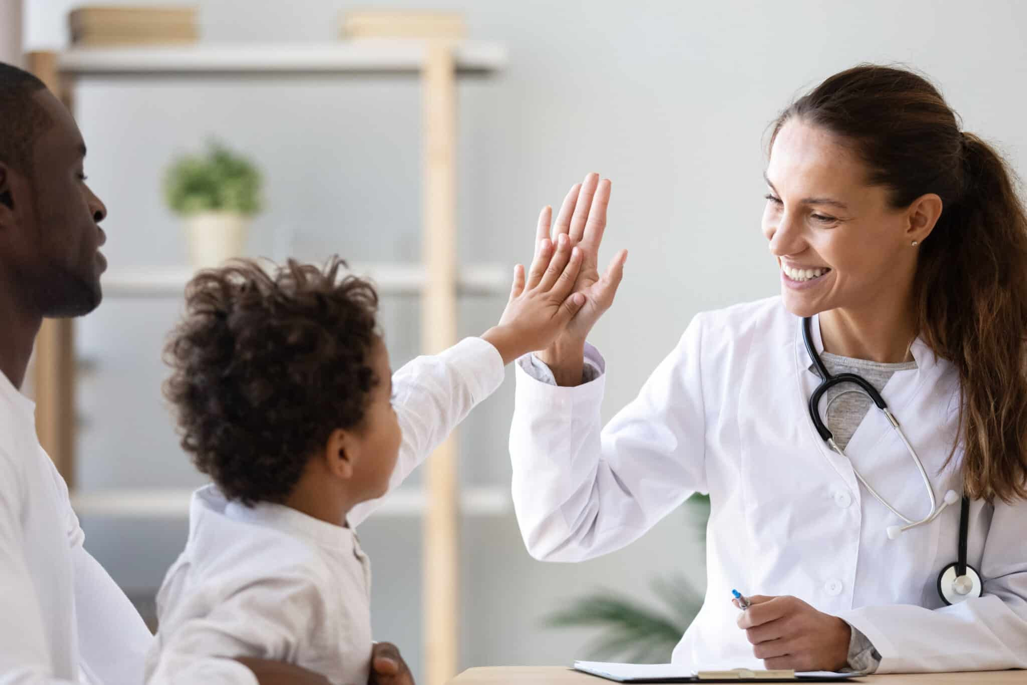 Doctor giving a young patient a high five during a medical visit