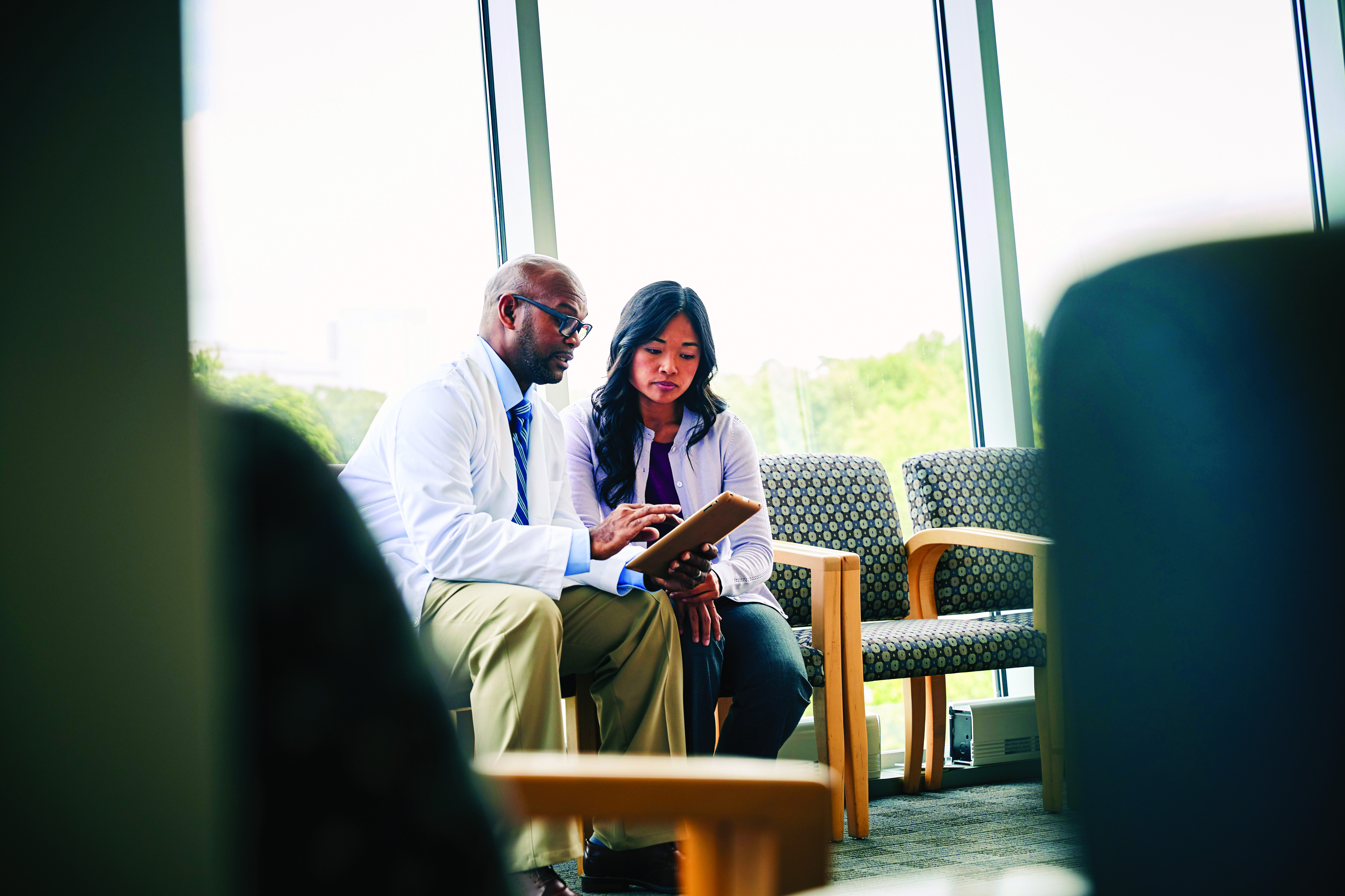 Healthcare provider using AI-enabled digital tools on a tablet to guide patient through insurance coverage, financial counseling, and revenue cycle support