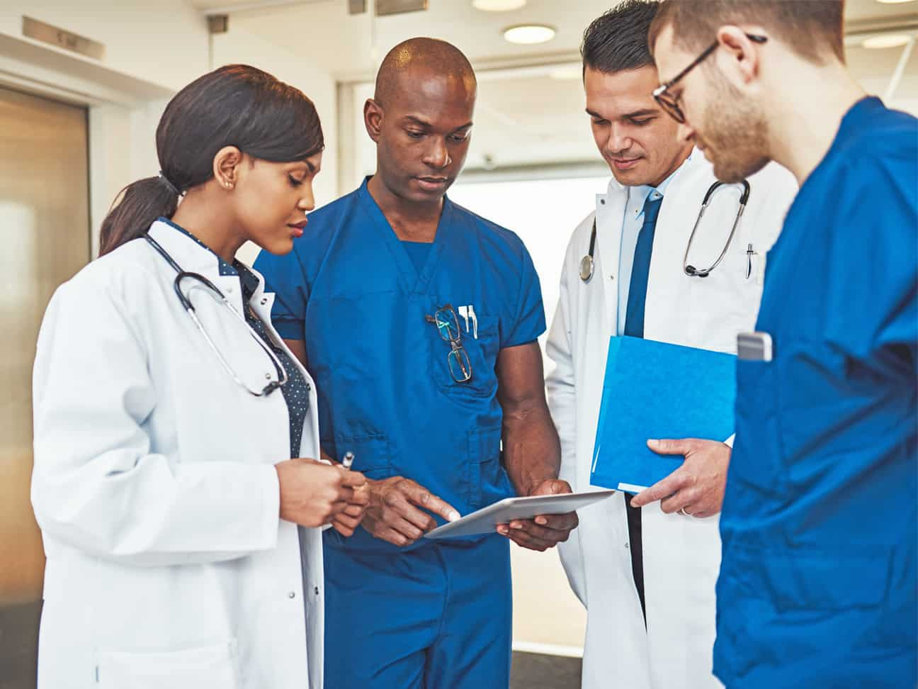 Healthcare professionals reviewing patient information on a tablet to support care coordination, clinical collaboration, and operational efficiency