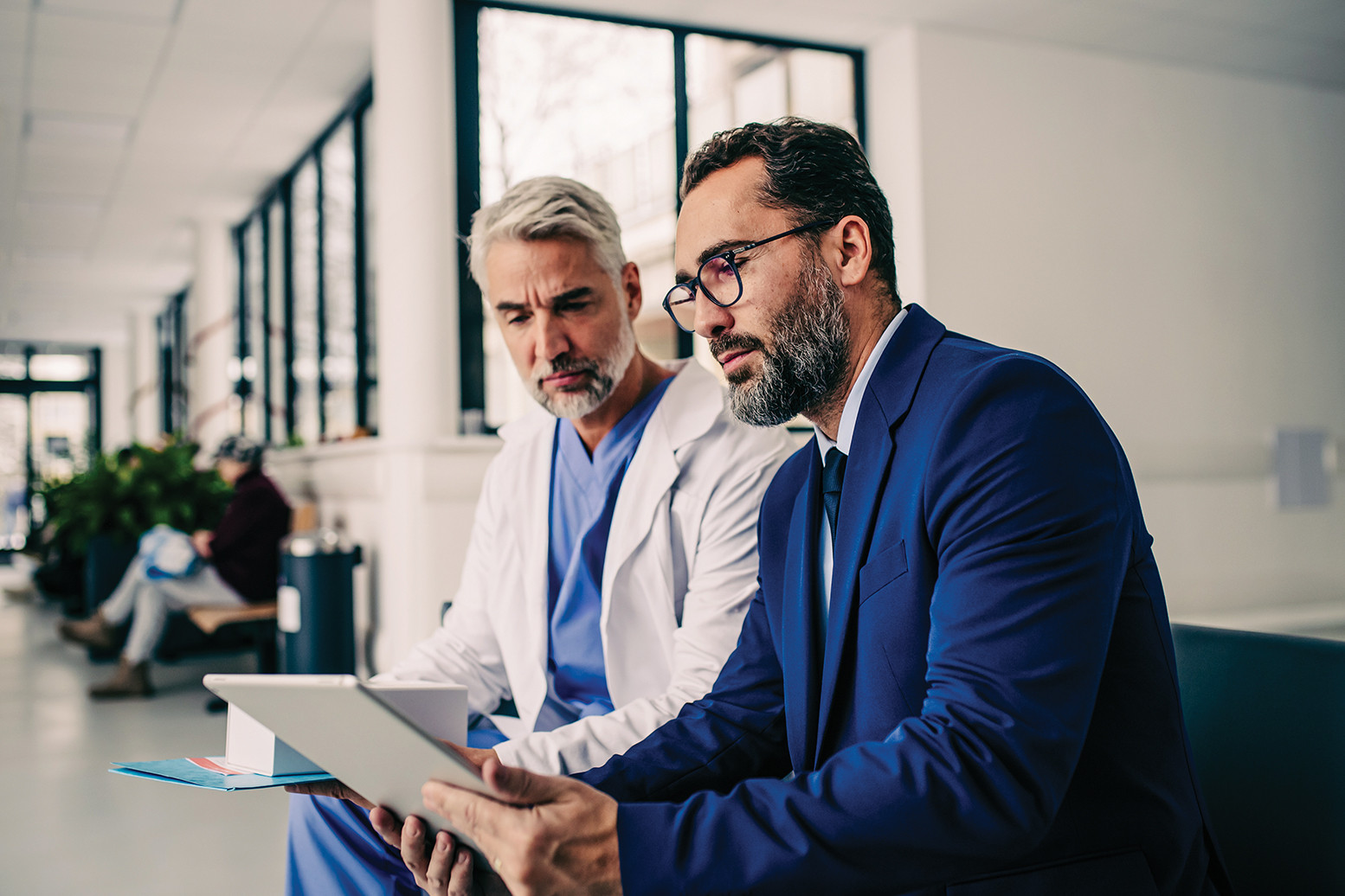 Physician and healthcare professional reviewing patient data on a tablet to support clinical decisions and improve care outcomes.