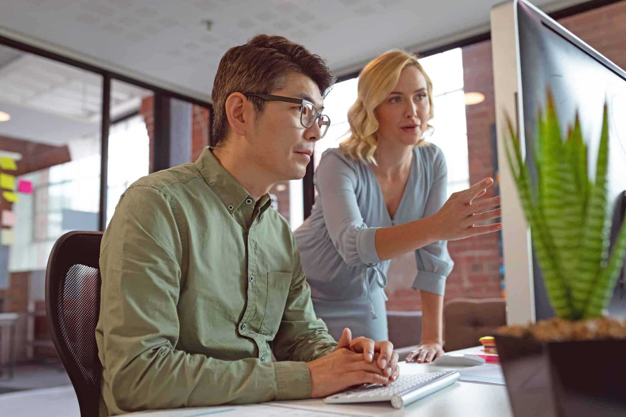 Two professionals collaborating at a computer in a modern office workspace