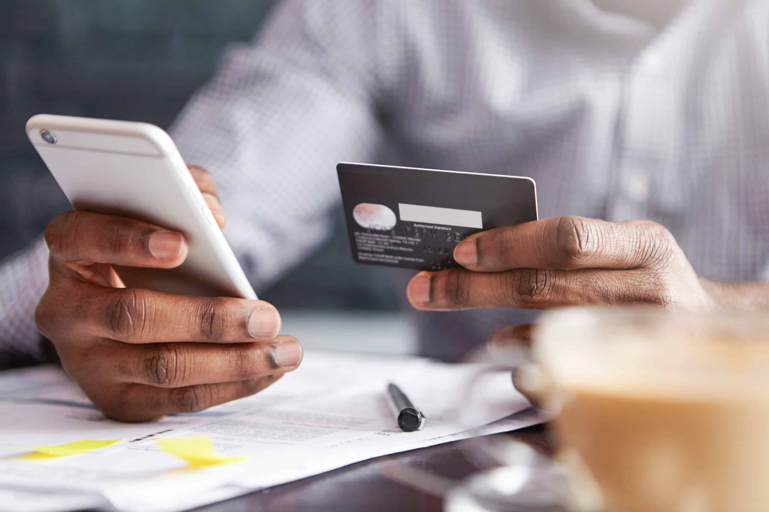 Person using a smartphone and credit card to make an online payment, representing digital billing and payment processing.