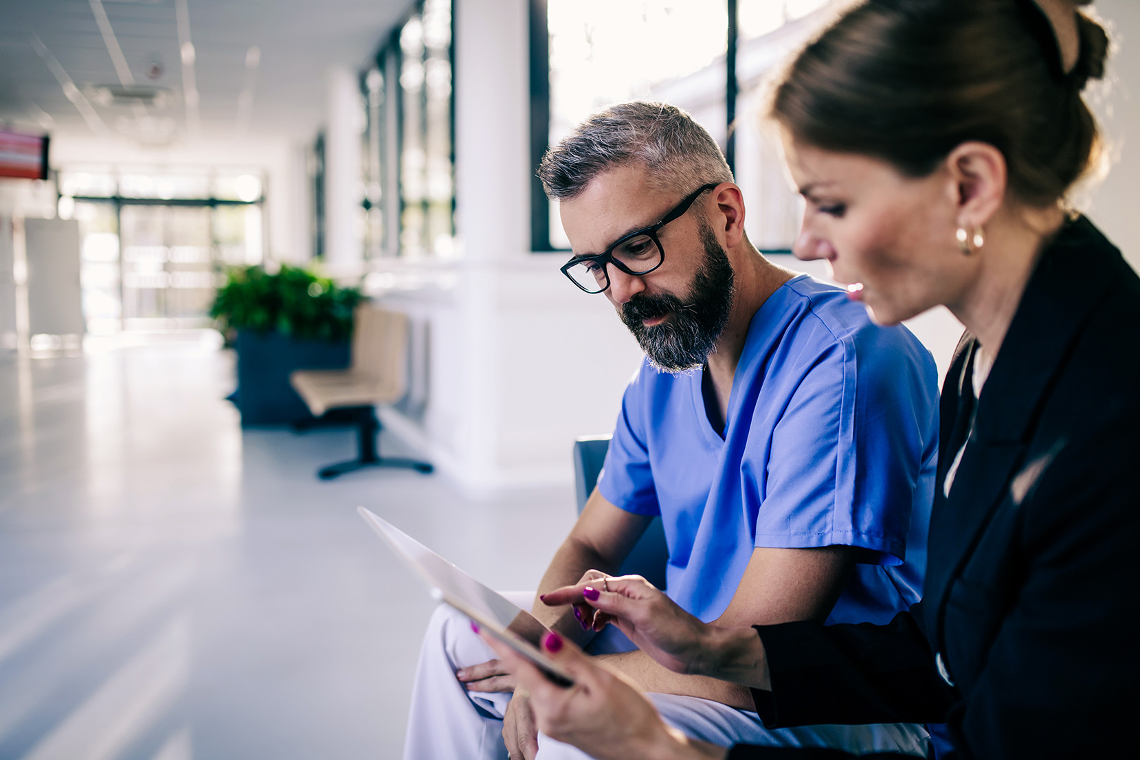 Revenue cycle management expert talking with doctor in medical building. Ambitious female sales representative presenting new technology. Woman business leader.