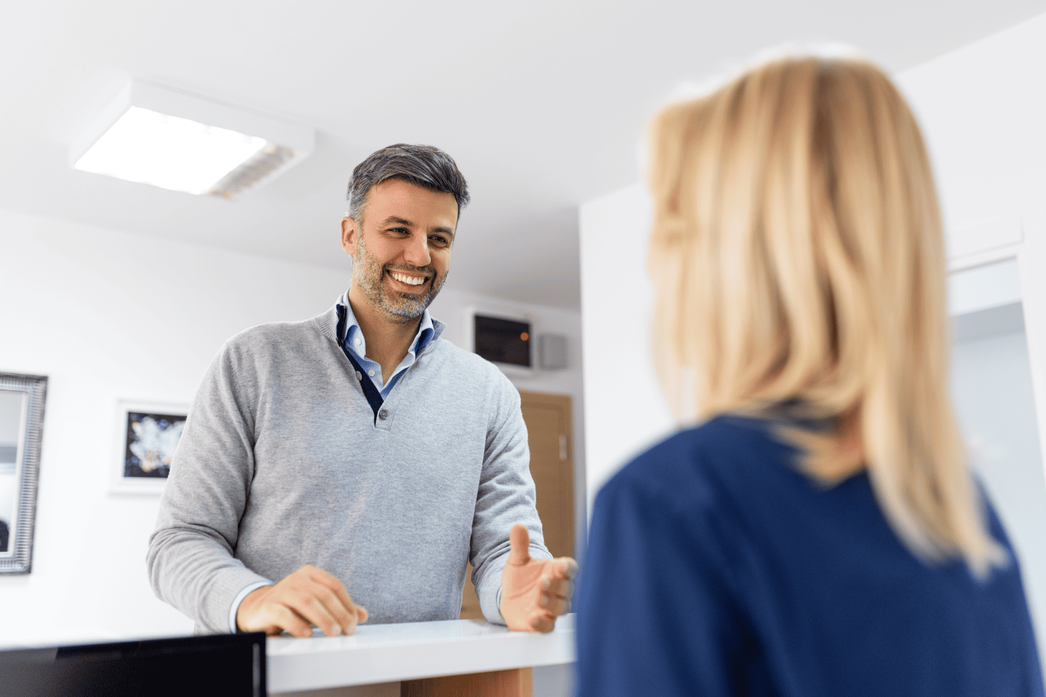 Patient speaking with a healthcare staff member at a reception desk