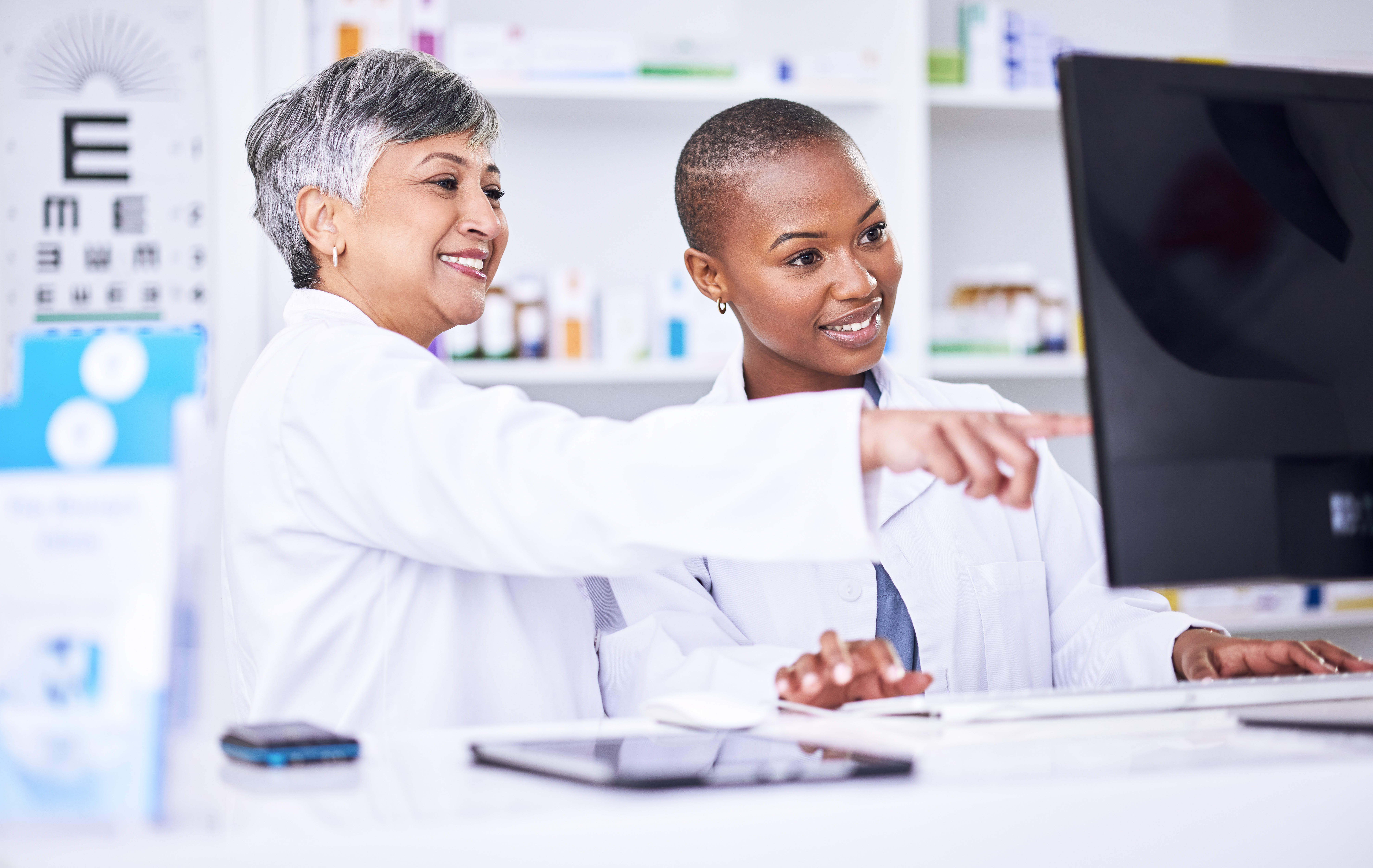 Healthcare professionals reviewing patient information on a computer in a clinical setting.