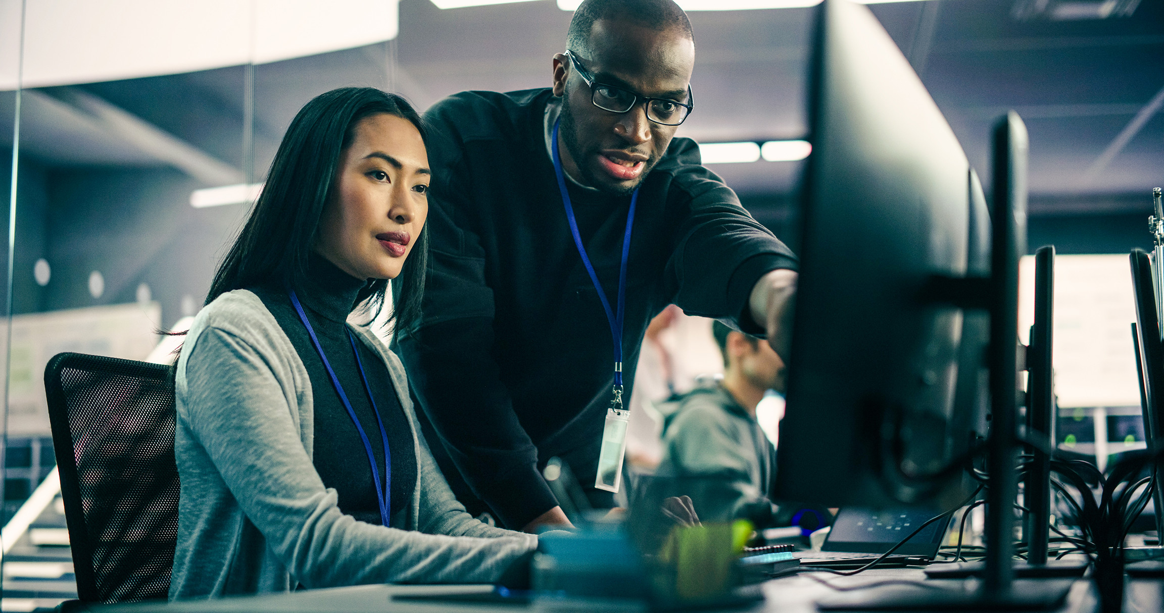 Two Diverse Multiethnic Colleagues Having a Conversation While Busy Working on a Team Project. Asian Female Designer Talking with an African Project Manager. Teamwork in Technology Laboratory