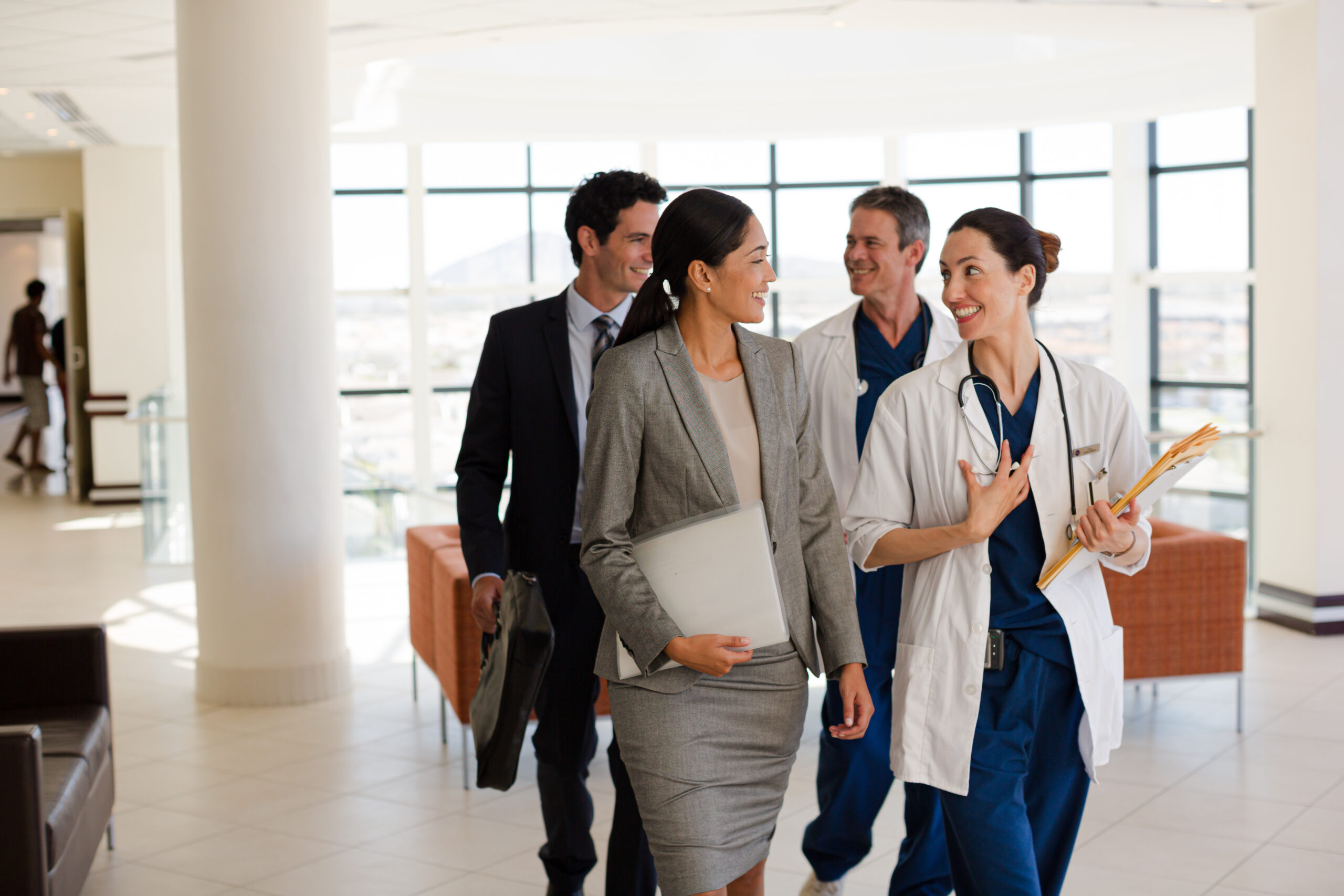 Healthcare professionals and hospital administrators walking together, discussing care coordination in a modern medical facility.