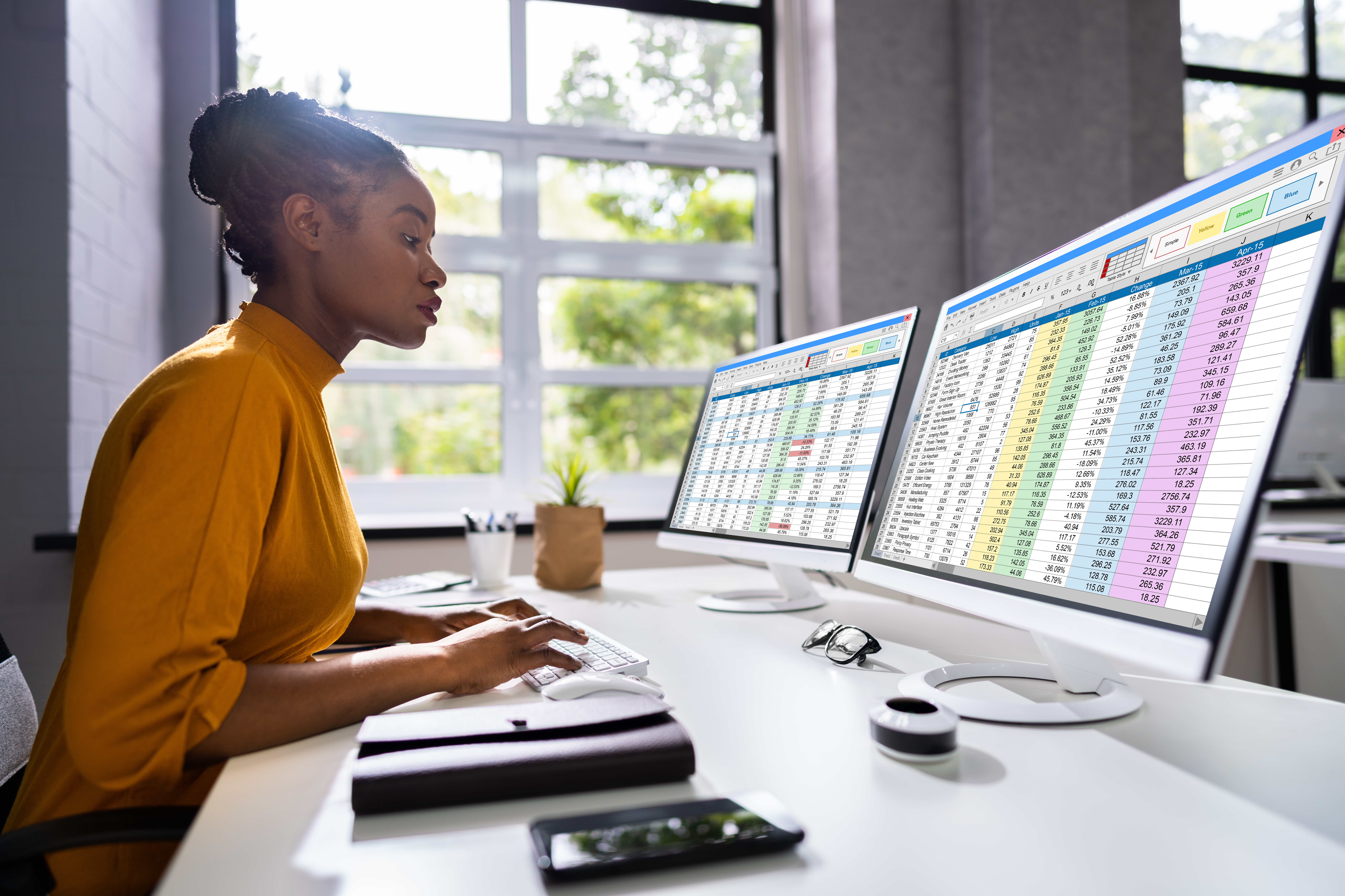 Professional using dual screens to analyze data in a modern workspace.