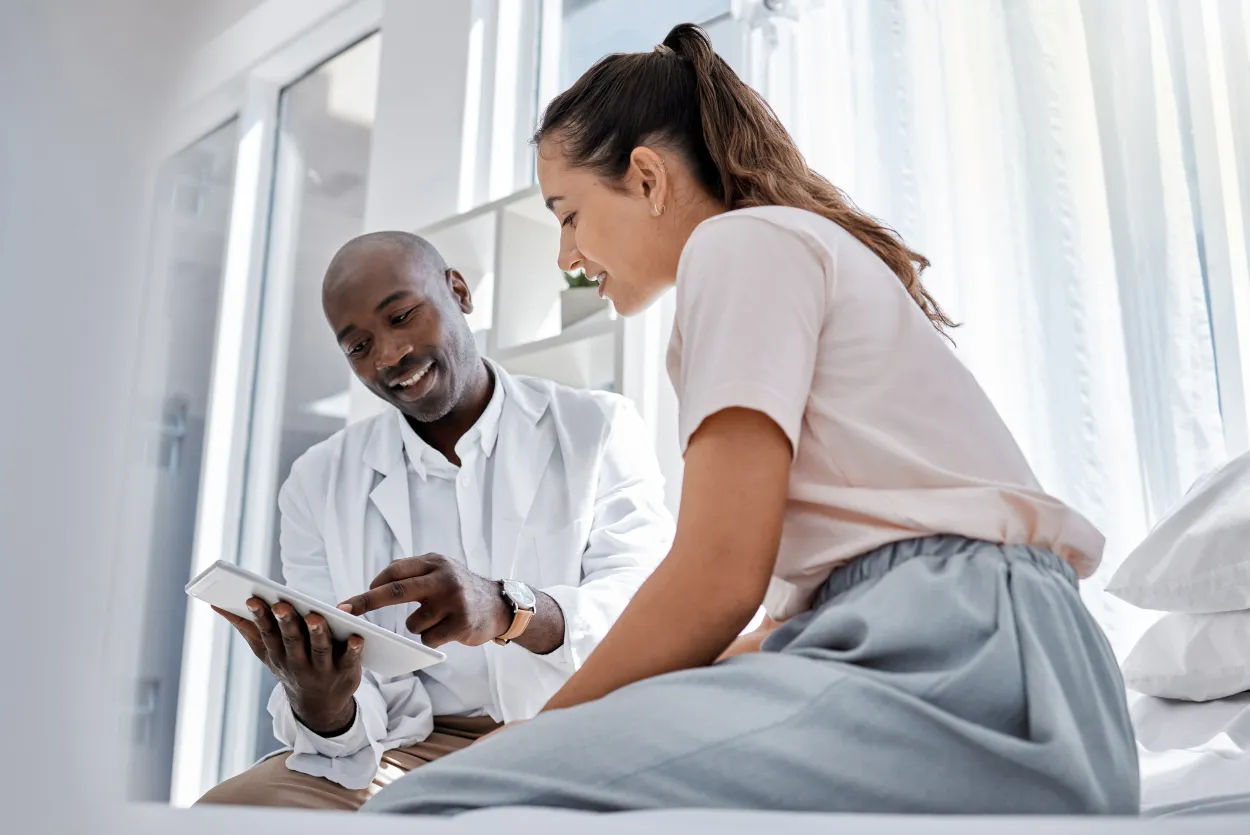 Healthcare professional reviewing information with a patient using a tablet to support care coordination, engagement, and a positive patient experience