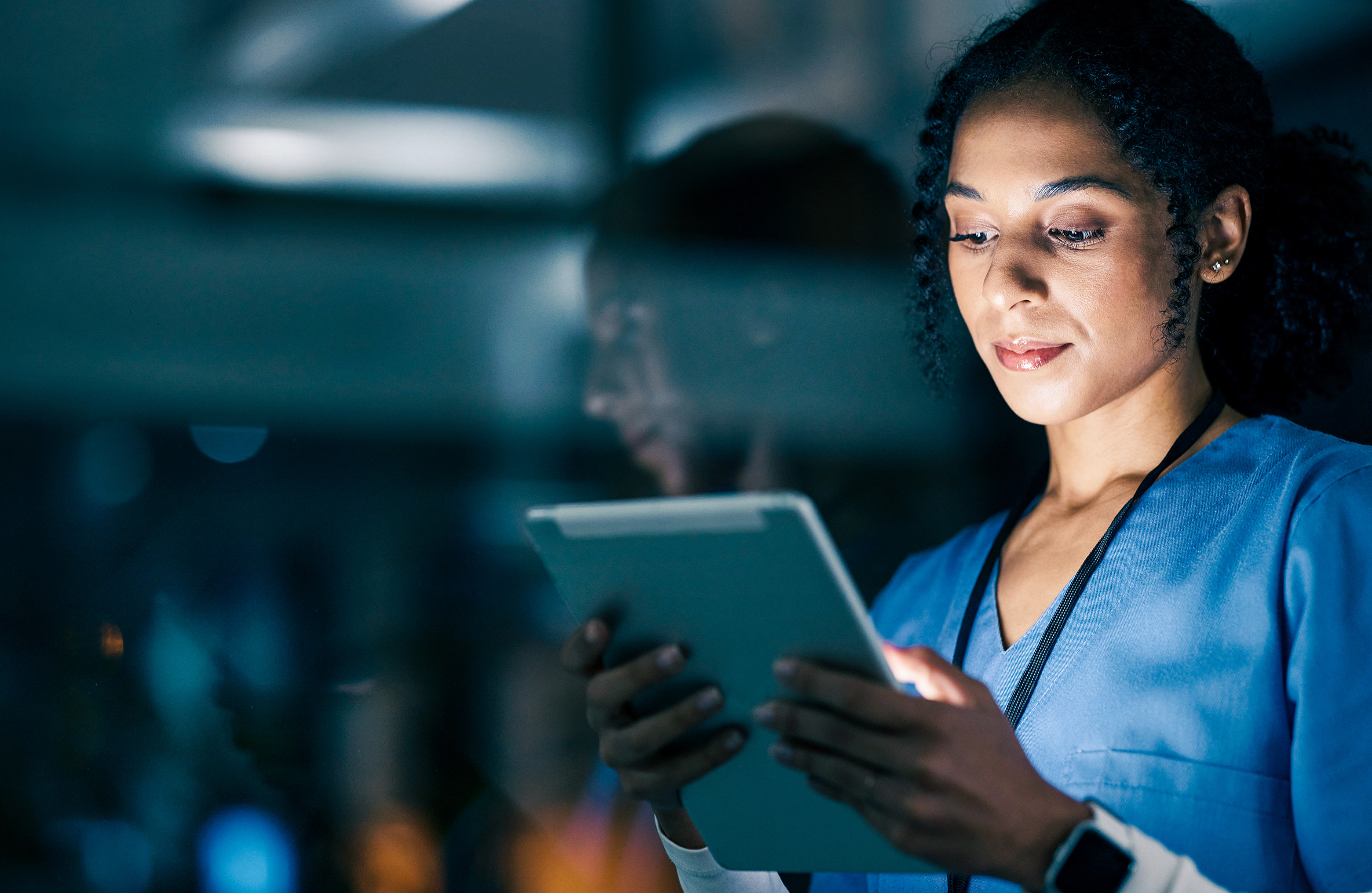 Healthcare worker using digital technology to access patient information in a clinical setting.