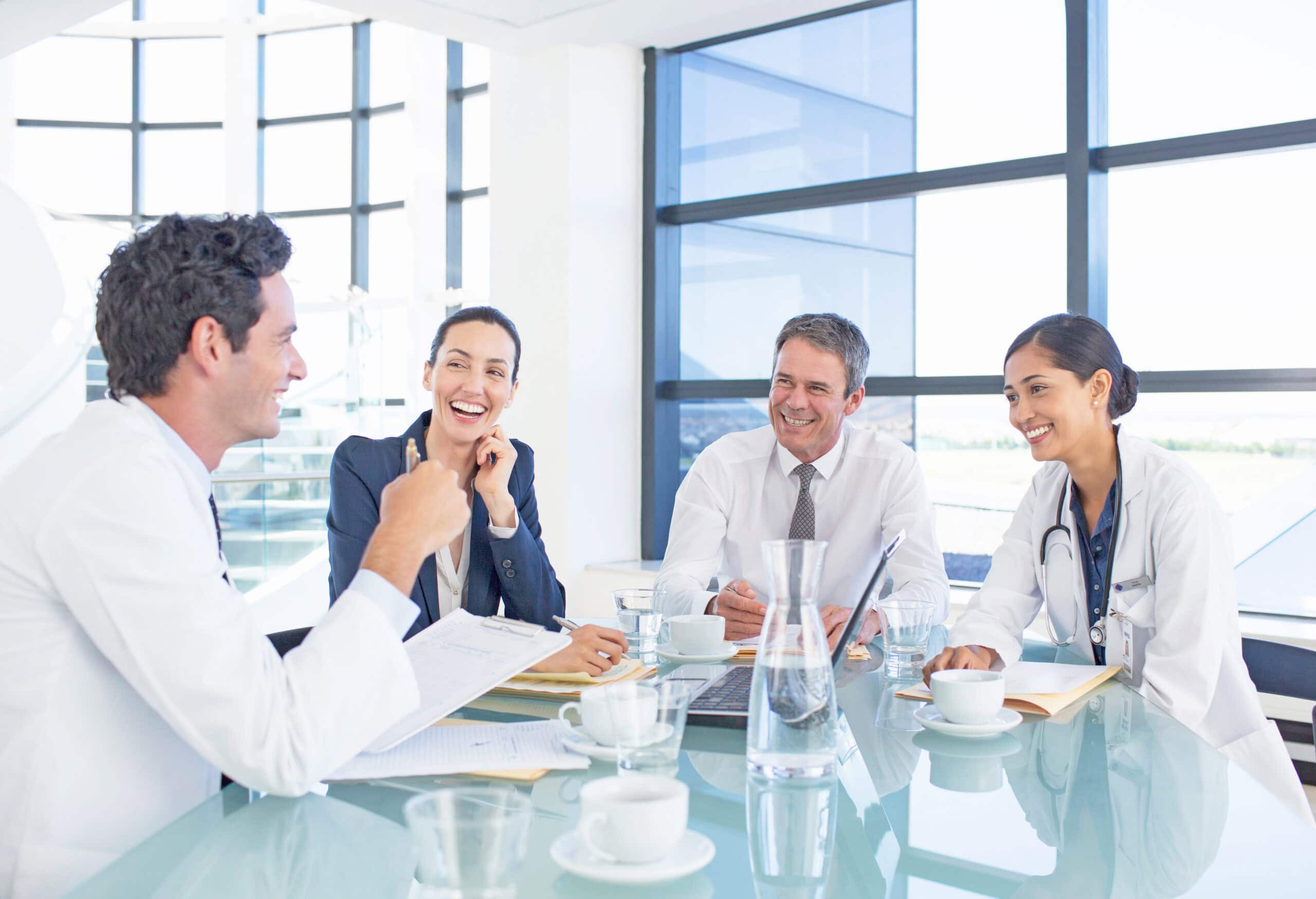 Healthcare professionals and administrators meeting around a conference table, discussing collaboration, patient care, and operational strategy.