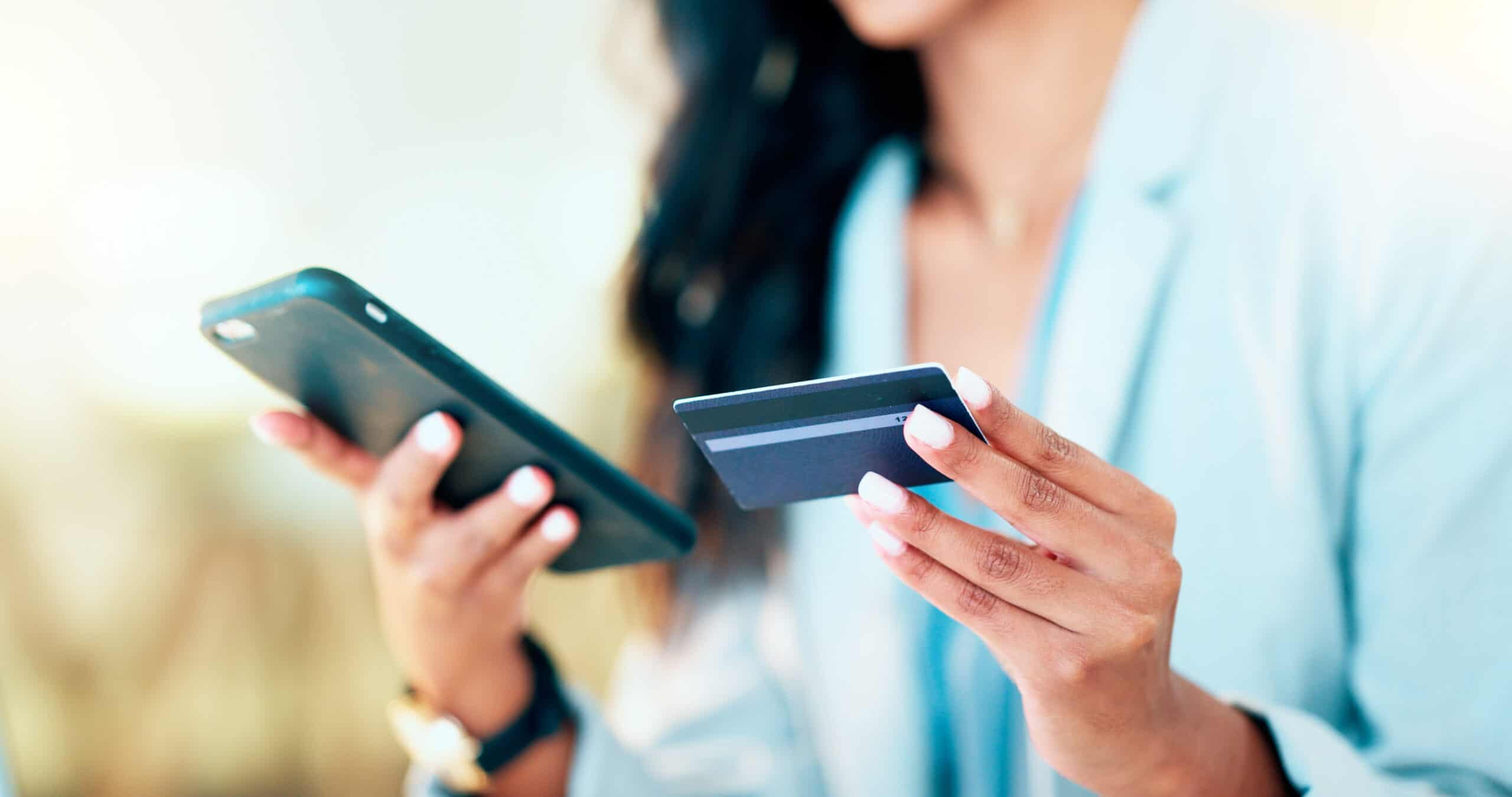 Person using a smartphone and credit card to make a digital payment, representing online billing and mobile transactions.