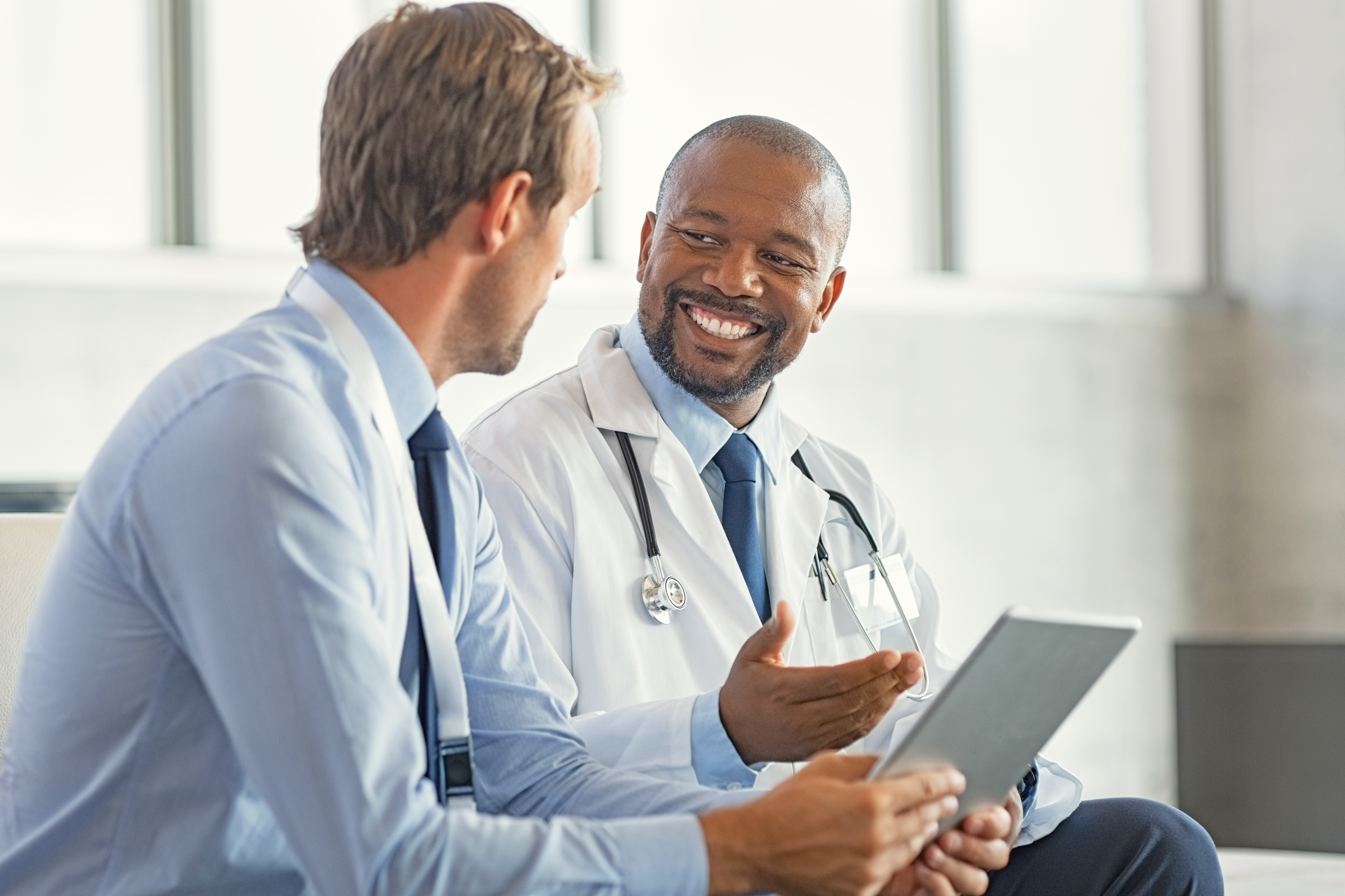 Clinical leader reviewing healthcare systems information on a tablet during a collaborative discussion.