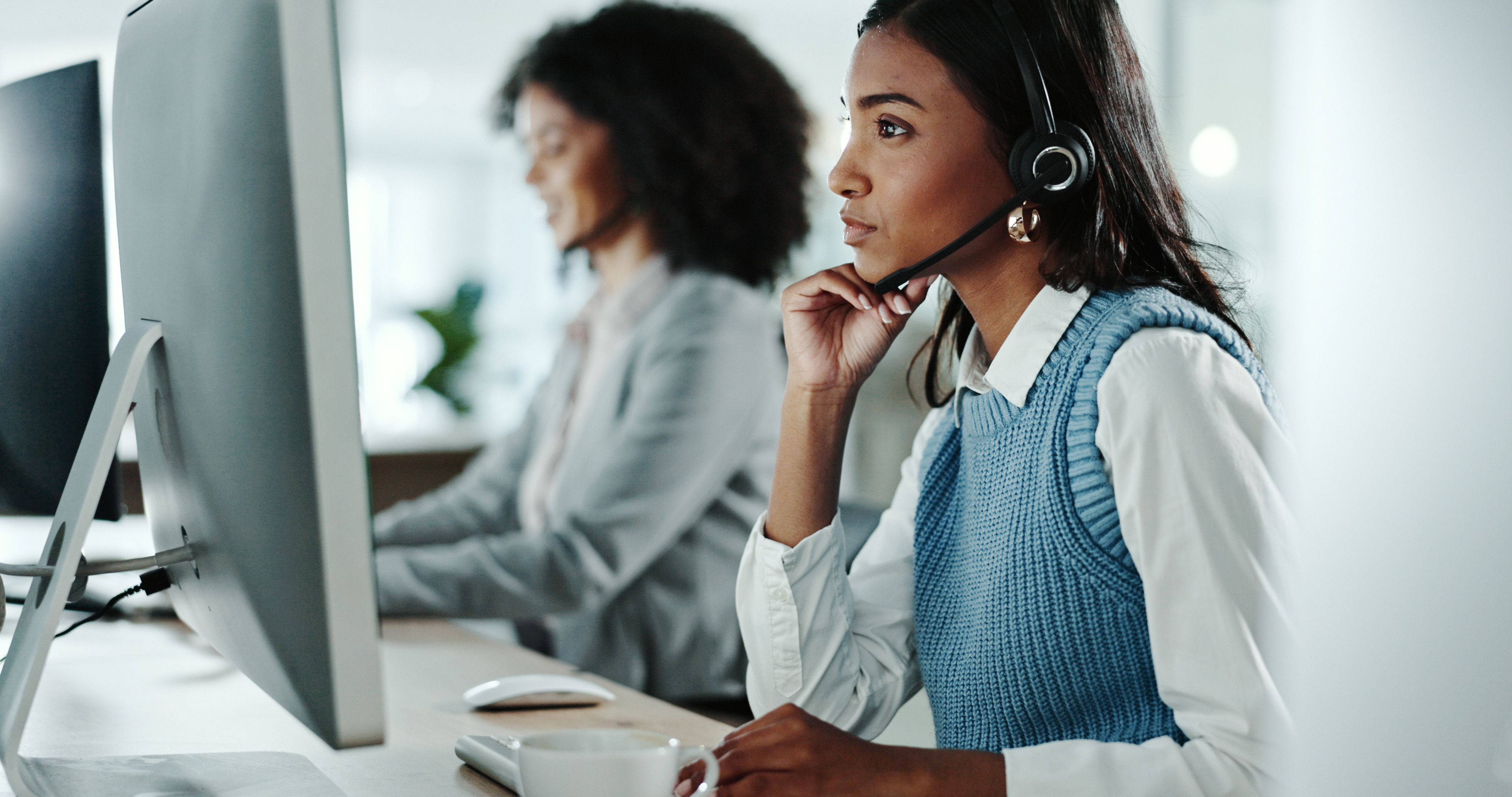 Healthcare support professional assisting with technology-enabled healthcare operations at a computer workstation.
