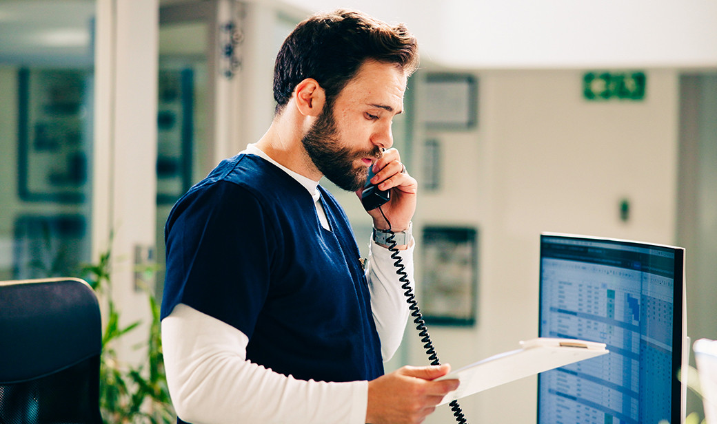 Healthcare professional reviewing paperwork while speaking on the phone