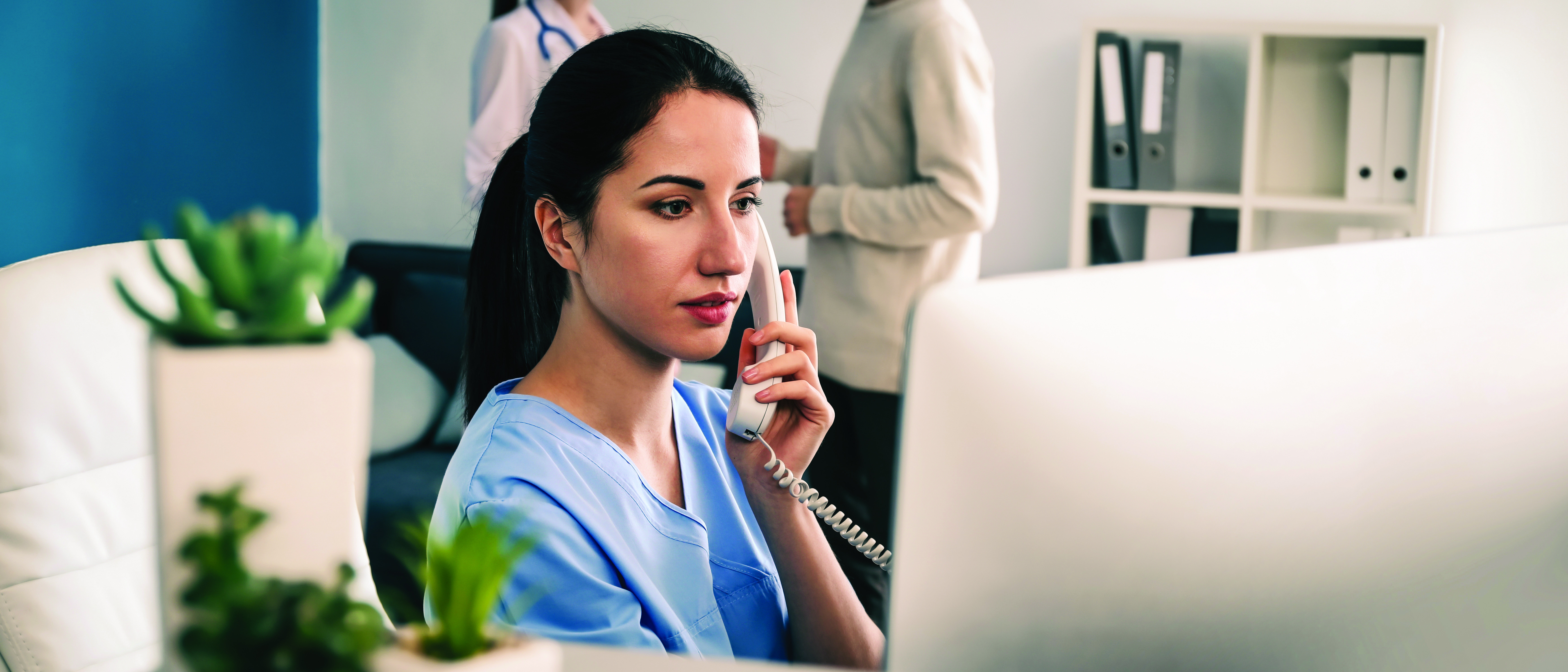 Female receptionist talking by phone in clinic
