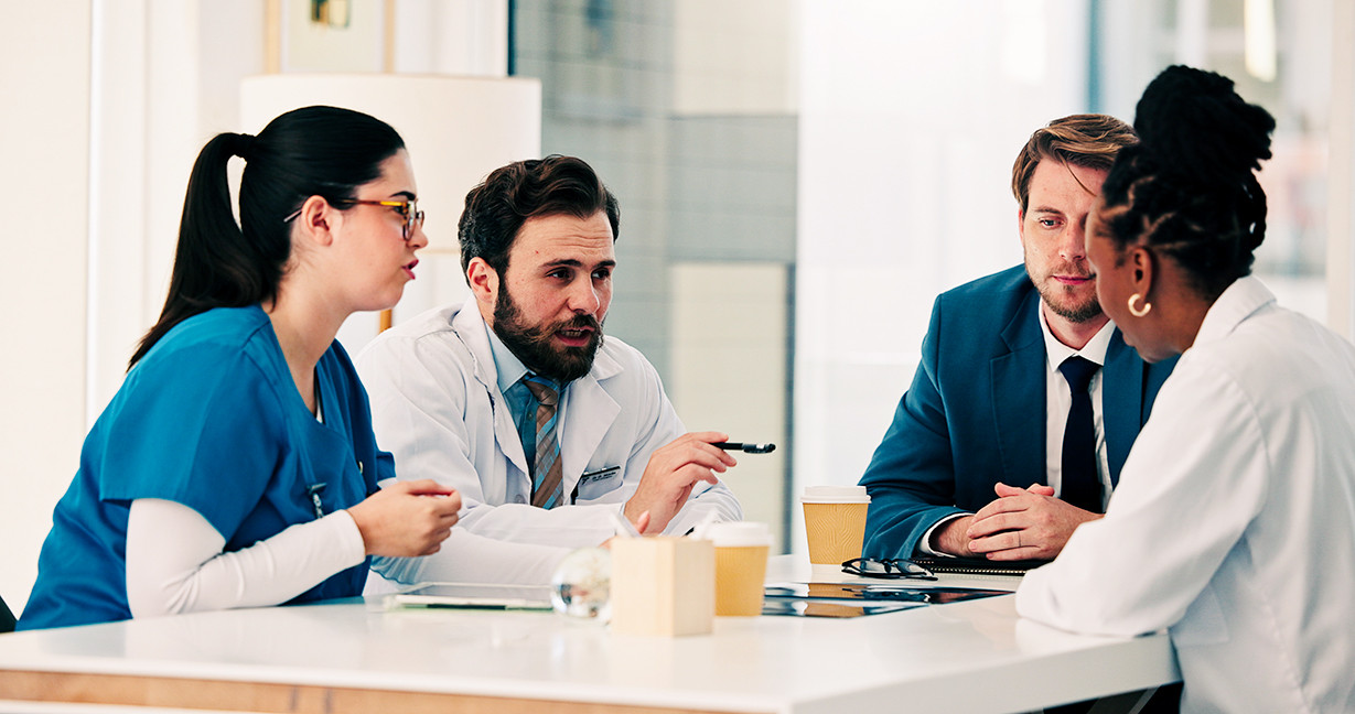 Businessman, doctors and nurse with meeting in clinic for research grant, vaccine trial or planning. Healthcare, people and staff with discussion for medical funding, investment opportunity or update