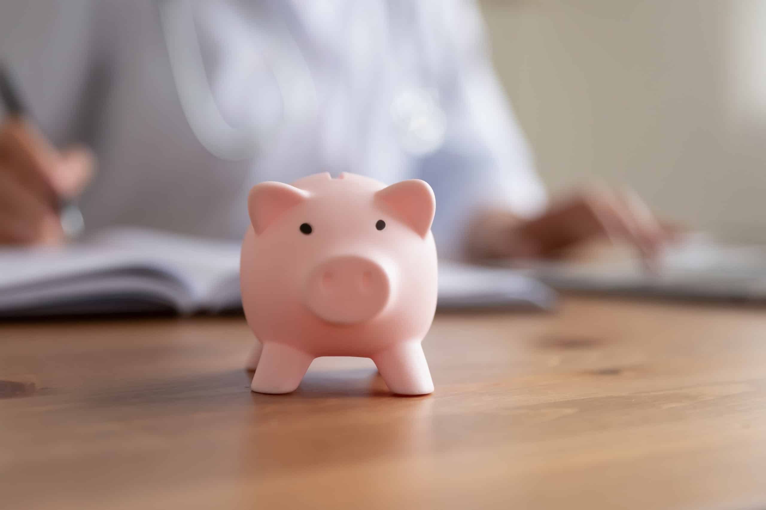 Crop close up of piggy bank on wooden table in hospital or private clinic for monetary donation