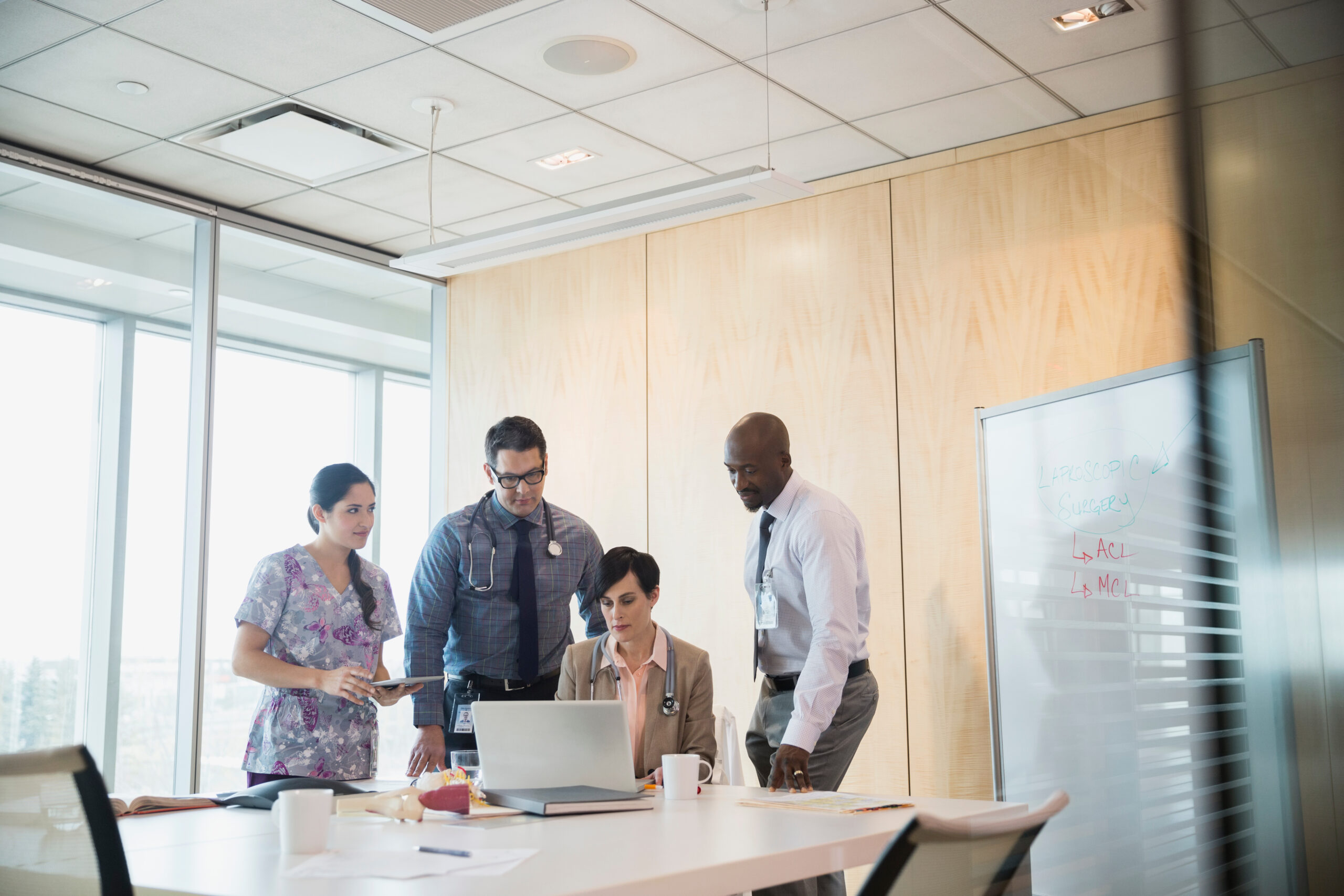 Doctors meeting around laptop in hospital conference room