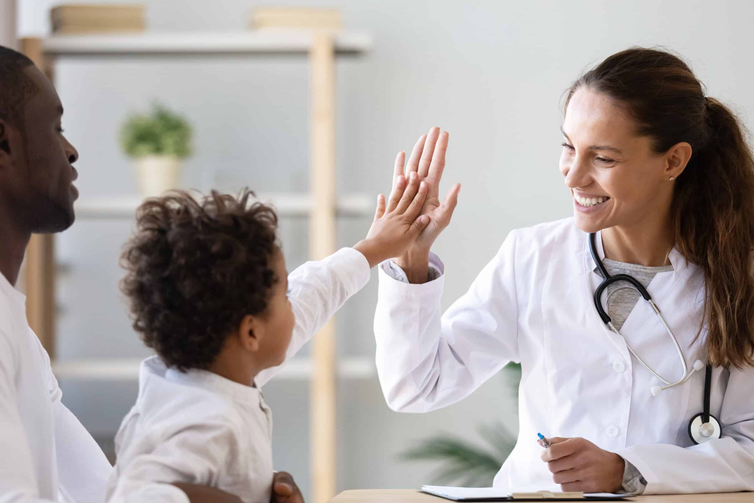 Smiling female doctor give high five to little biracial patient