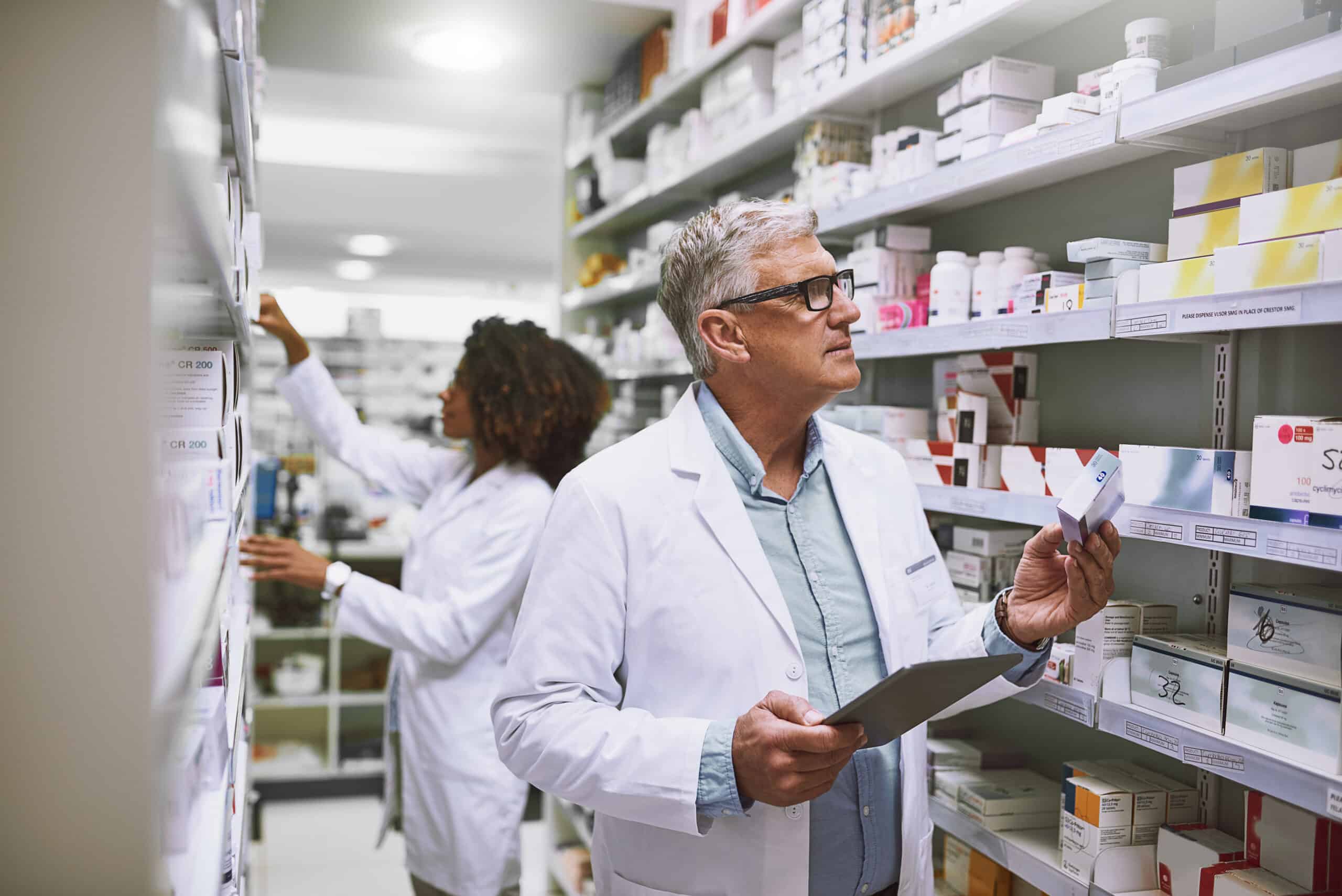 Stocking up. Shot of two focused pharmacist walking around and doing stock inside of a pharmacy.